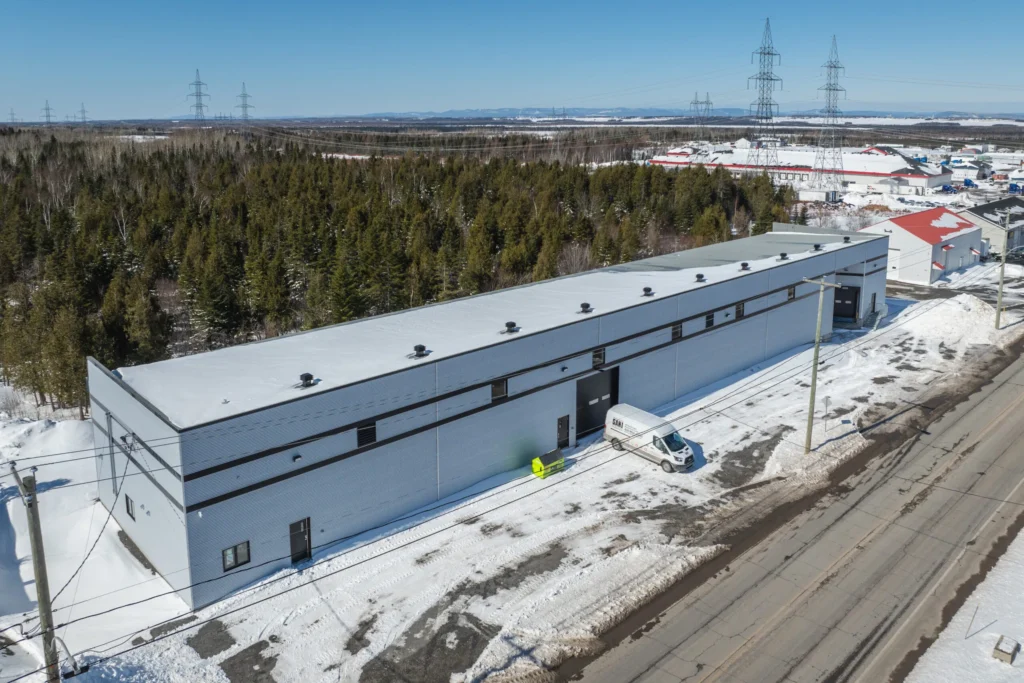 Entrepôt blanc dédié à l'emballage alimentaire et produits sanitaires, neige et utilitaire stationné devant.