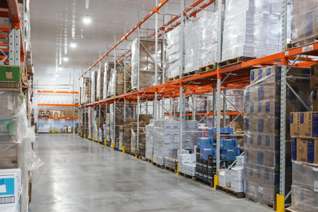 Entrepôt lumineux avec rayonnages orange, produits sanitaires, emballages et solutions écologiques de nettoyage.