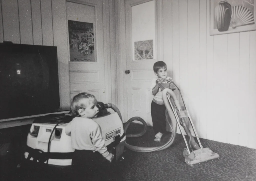 Enfants testant un aspirateur écologique dans une pièce boisée, nettoyage professionnel.